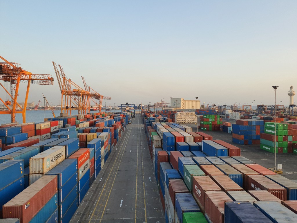 Stacked shipping containers lining a terminal roadway at a cargo port